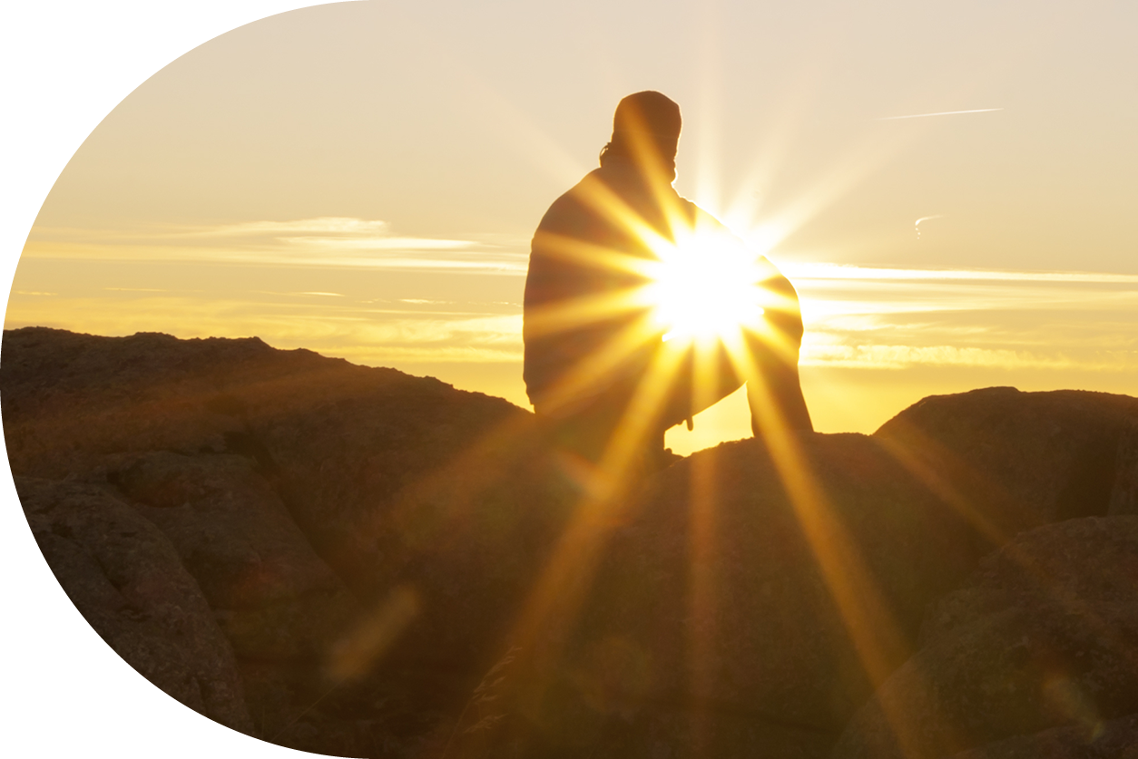 silhouette on cliff watching sunset