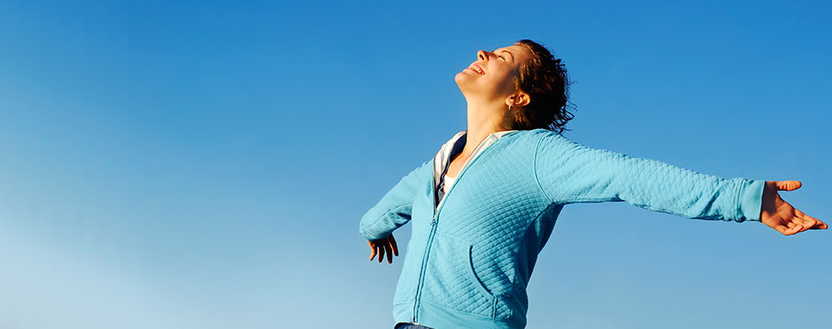 woman standing with arms stretched out facing the sunshine