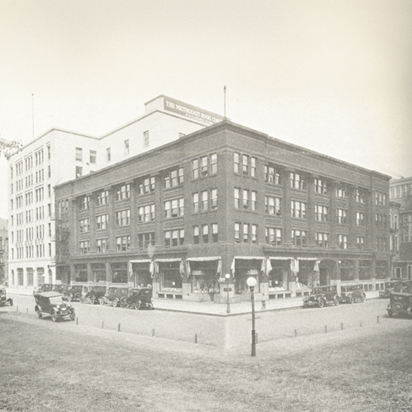 Sepia toned photo of the street view of three story building.