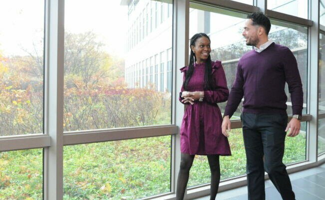 Two people walking through office talking