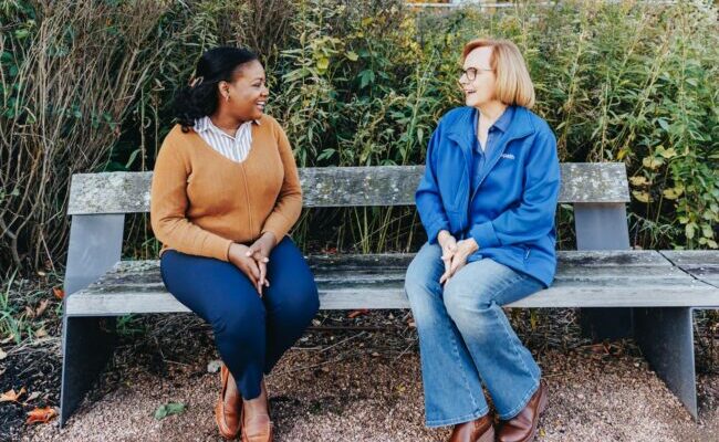 Two women sitting on a park bench talking