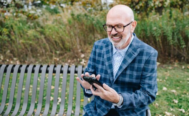 Man sitting at bench outside on phone