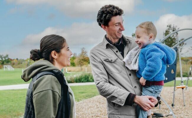 Dad holding child with Mom standing next to them