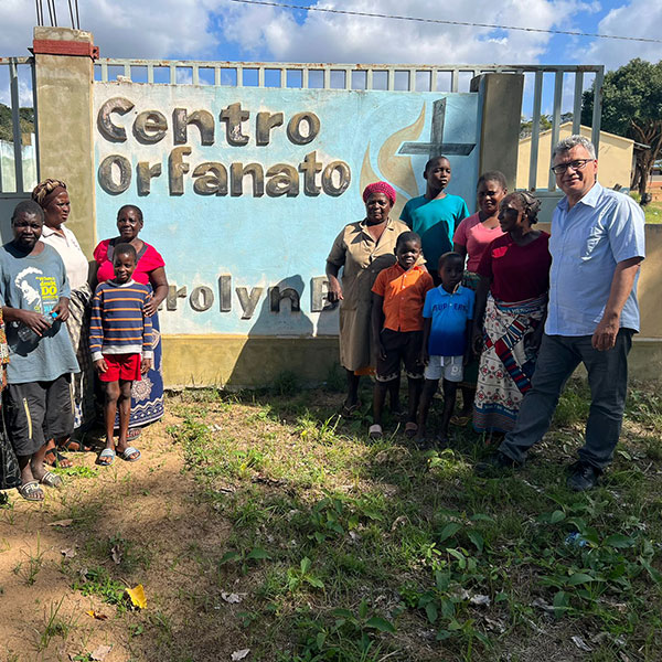 A group of people smiling and standing in front of a Centro Orfanato sign