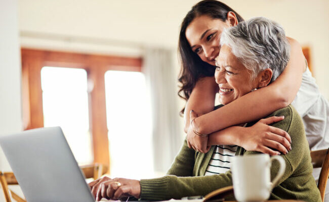 Woman hugging her mom who is on the computer