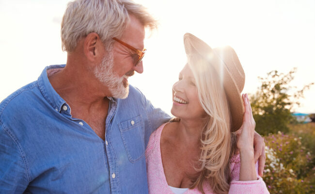 Loving Mature Couple In Countryside Hugging Against Flaring Sun