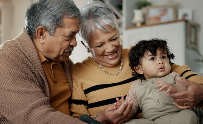Grandparents, grandchild and home with baby, babysitting and spending quality time while bonding together, love and trust. Happy family, support and smiling on couch, retired and caring for child.