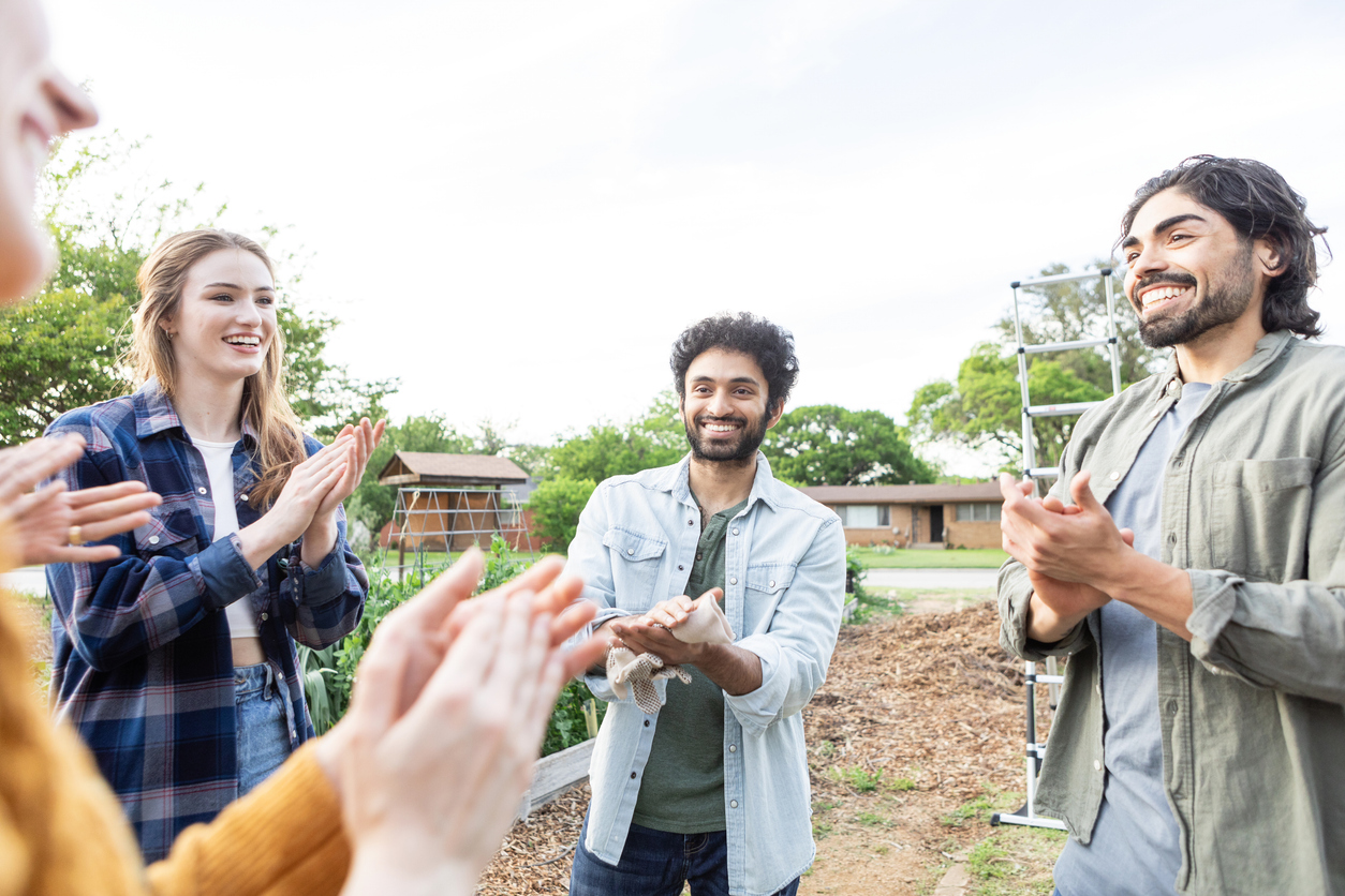 A group of people clapping hands in a circle outside
