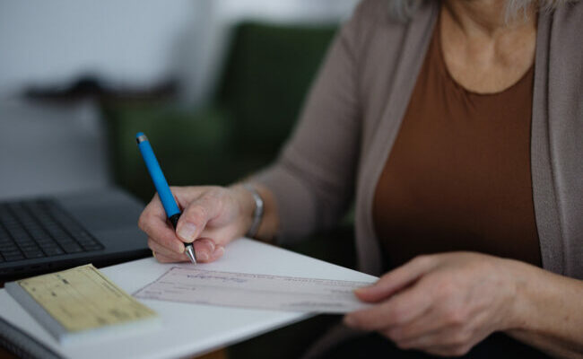 Professional Woman Writing Personal Checks in a Modern Office Space