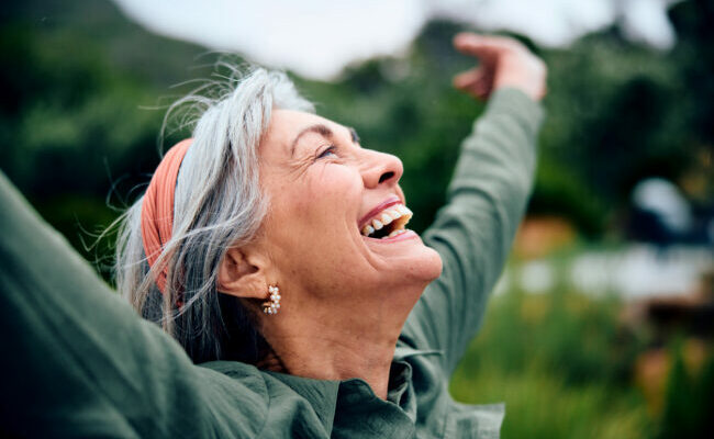 Portrait of carefree senior woman with arms out, looking up, smiling
