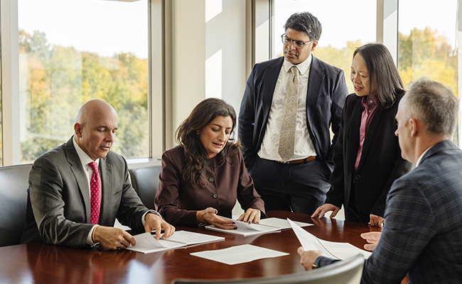 Five members of the investment team gathered around a table for a business meeting.
