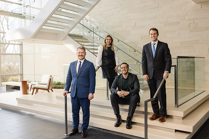 Four individuals members of the investments team standing in a lobby.