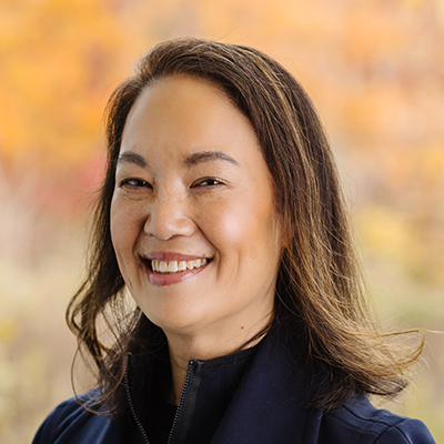 Portrait of Jennifer Seuring smiling. She has shoulder length brown hair and is working a black collared blouse and black blazer.