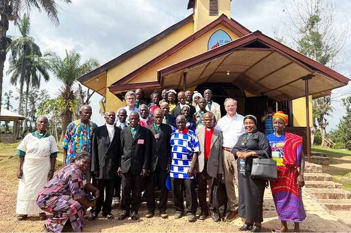 A group of people in colorful clothing in front of a church in Liberia.