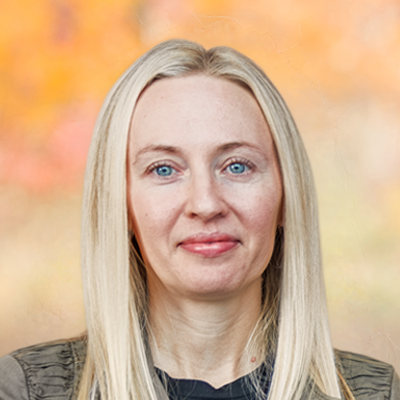 A portrait of Linda Meyer smiling. She has long blonde hair and is wearing a grey blazer and black blouse.