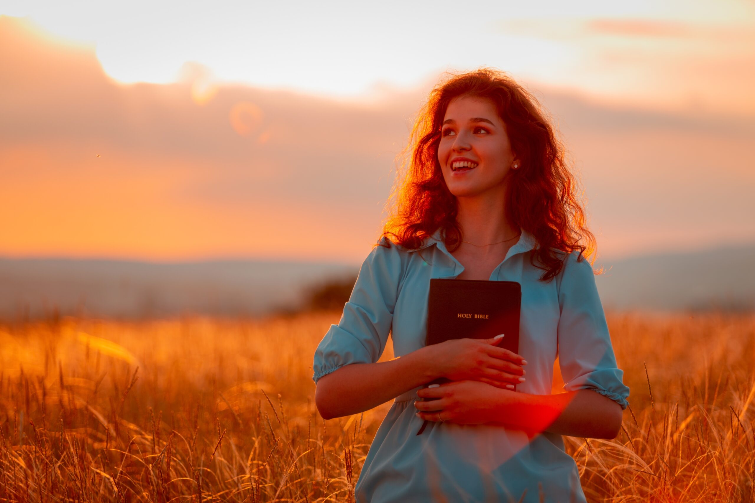 Christian woman holding bible in her hands in field