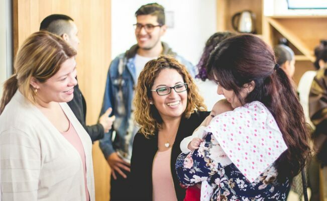 Two women looking at another woman's baby and smiling