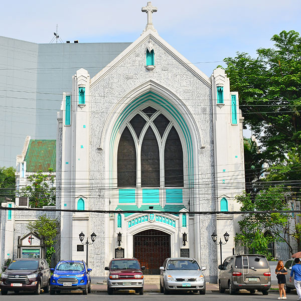 The outside entrance of a white church with teal accents.